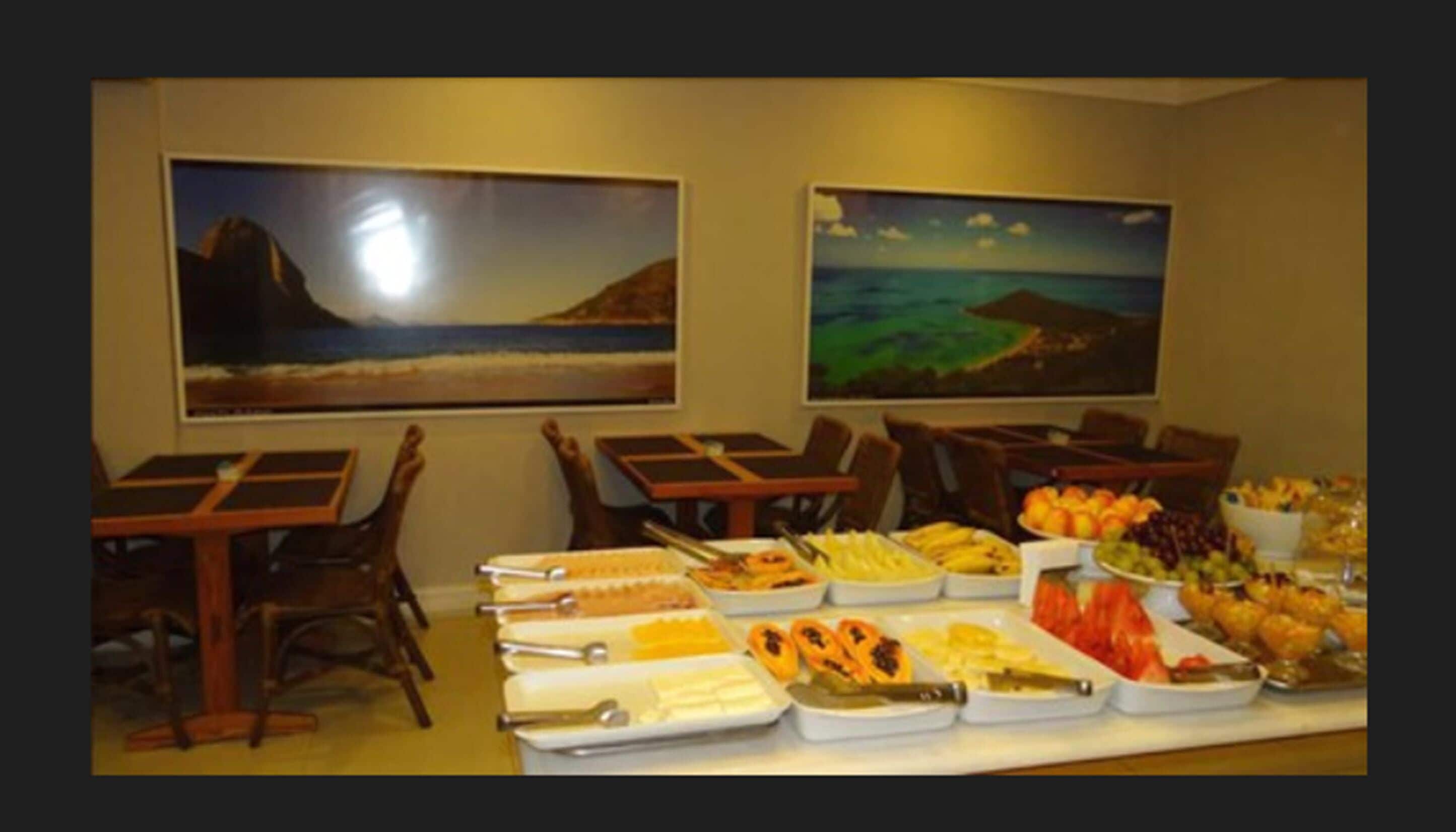 A buffet setup with various food items and two landscape paintings on the wall.