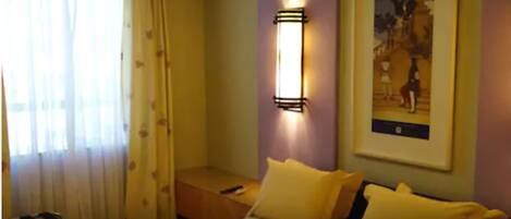 A hotel room with a bed, a nightstand, a lamp, and a painting on the wall.