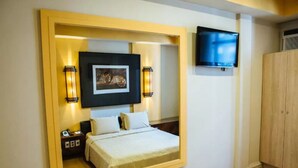 A bedroom with a bed, bedside table, lamp, and a TV mounted on the wall. - Diamond Hotel (Rio de Janeiro)