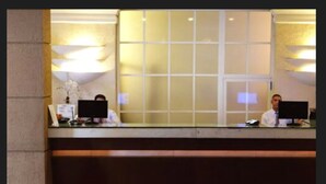 A reception desk with two computer monitors, a telephone, and a small plant. - Diamond Hotel (Rio de Janeiro)