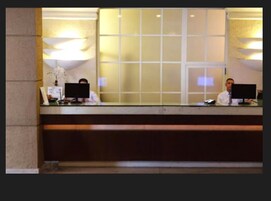 A reception desk with two computer monitors, a telephone, and a small plant.