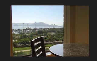 A view from a window overlooking a marina, greenery, and distant mountains.