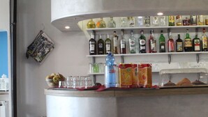 Una zona de bar con estantes llenos de botellas de licor, un frutero y vasos.