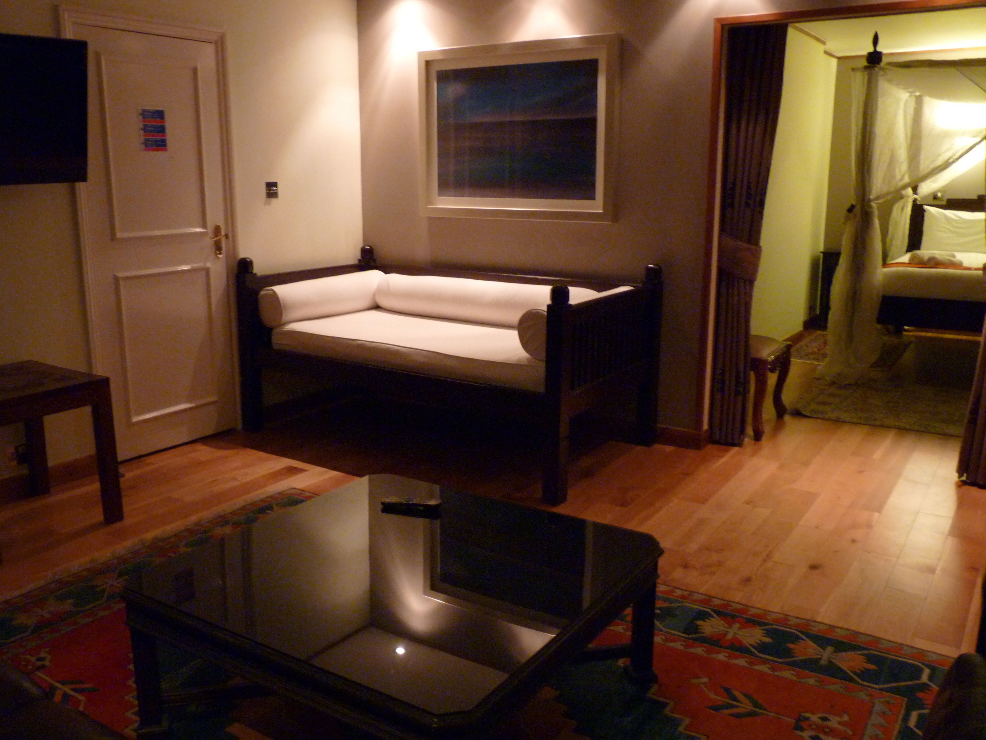 A room with a sofa, a glass-top table, a television, and a window.