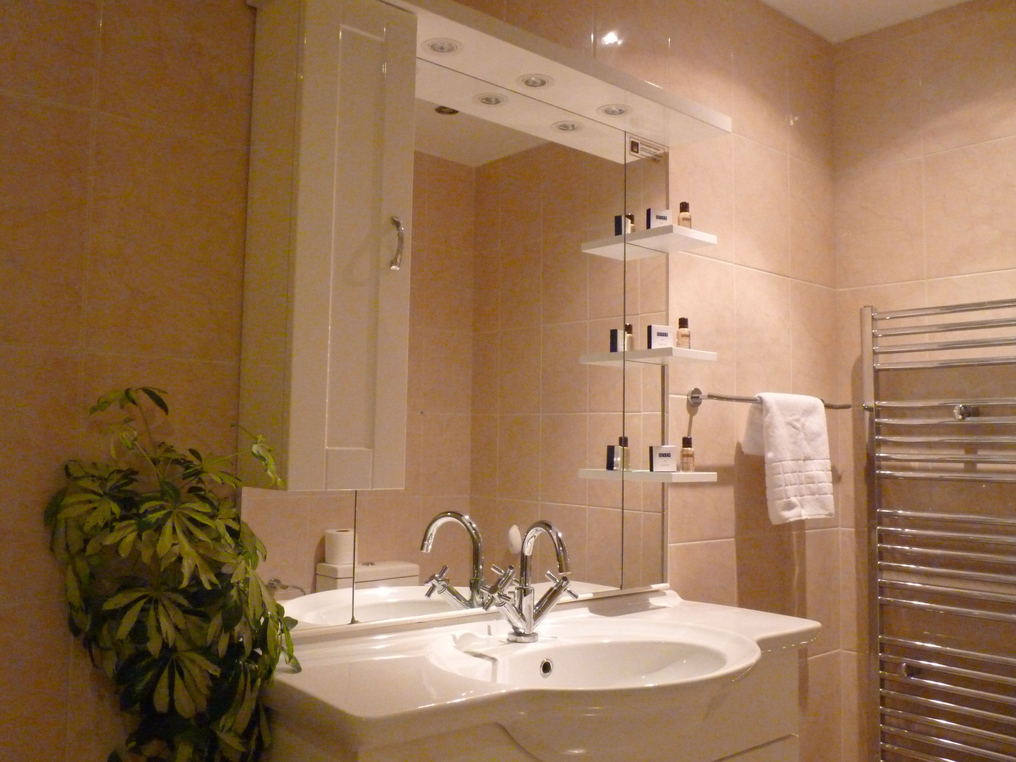 Un baño moderno con lavabo doble, un espejo grande y cabina de ducha con mampara de vidrio.