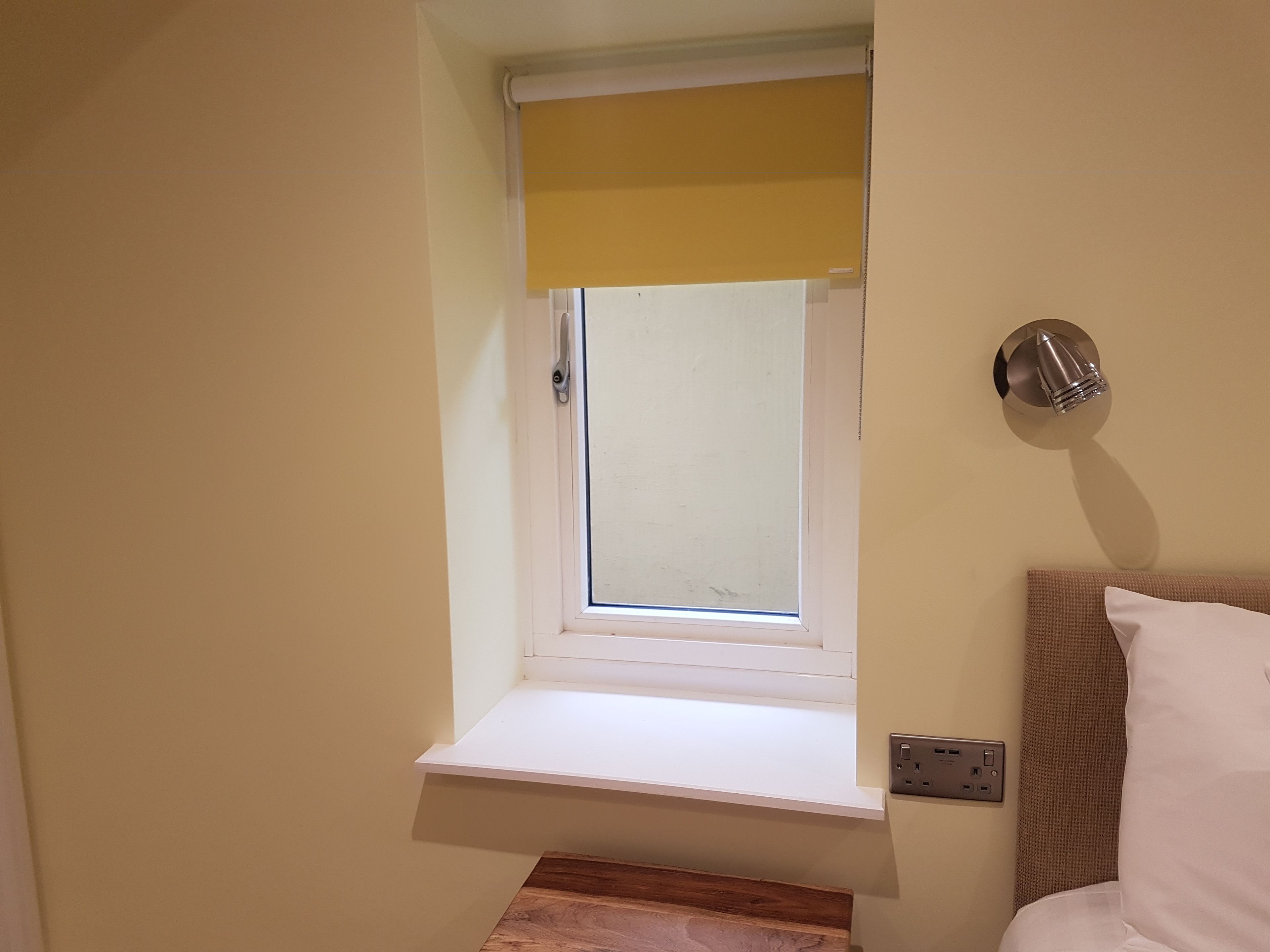 Ein Zimmer mit einem kleinen Fenster, einer Wandsteckdose und einer Steckdose.