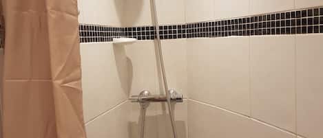 A shower with a handheld showerhead and a wall-mounted faucet.