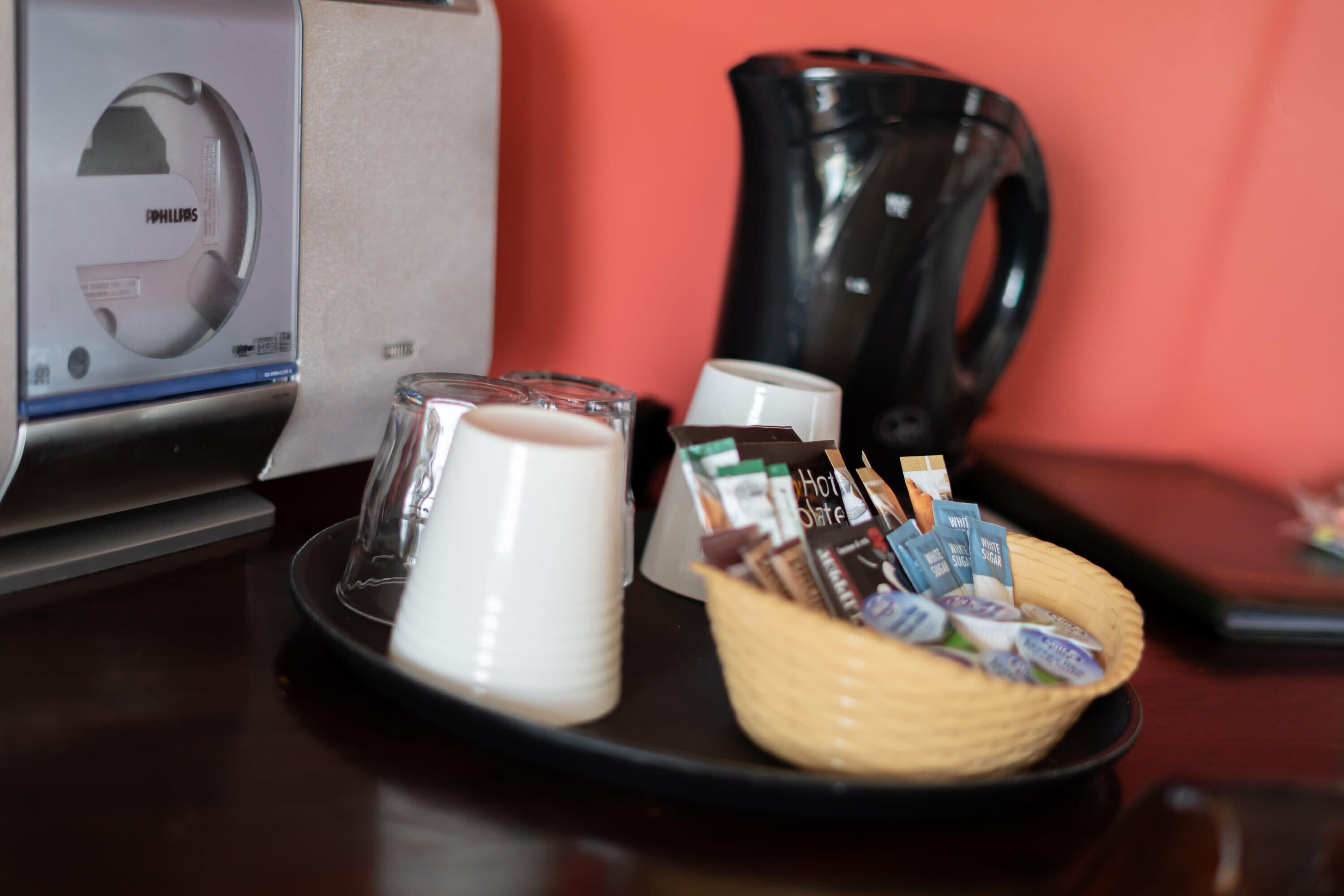 Une machine à café, un verre de lait et un panier de dosettes de café sur une table.