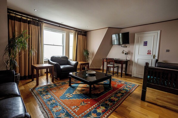 A living room with a sofa, a coffee table, a TV, and a door with a sign.