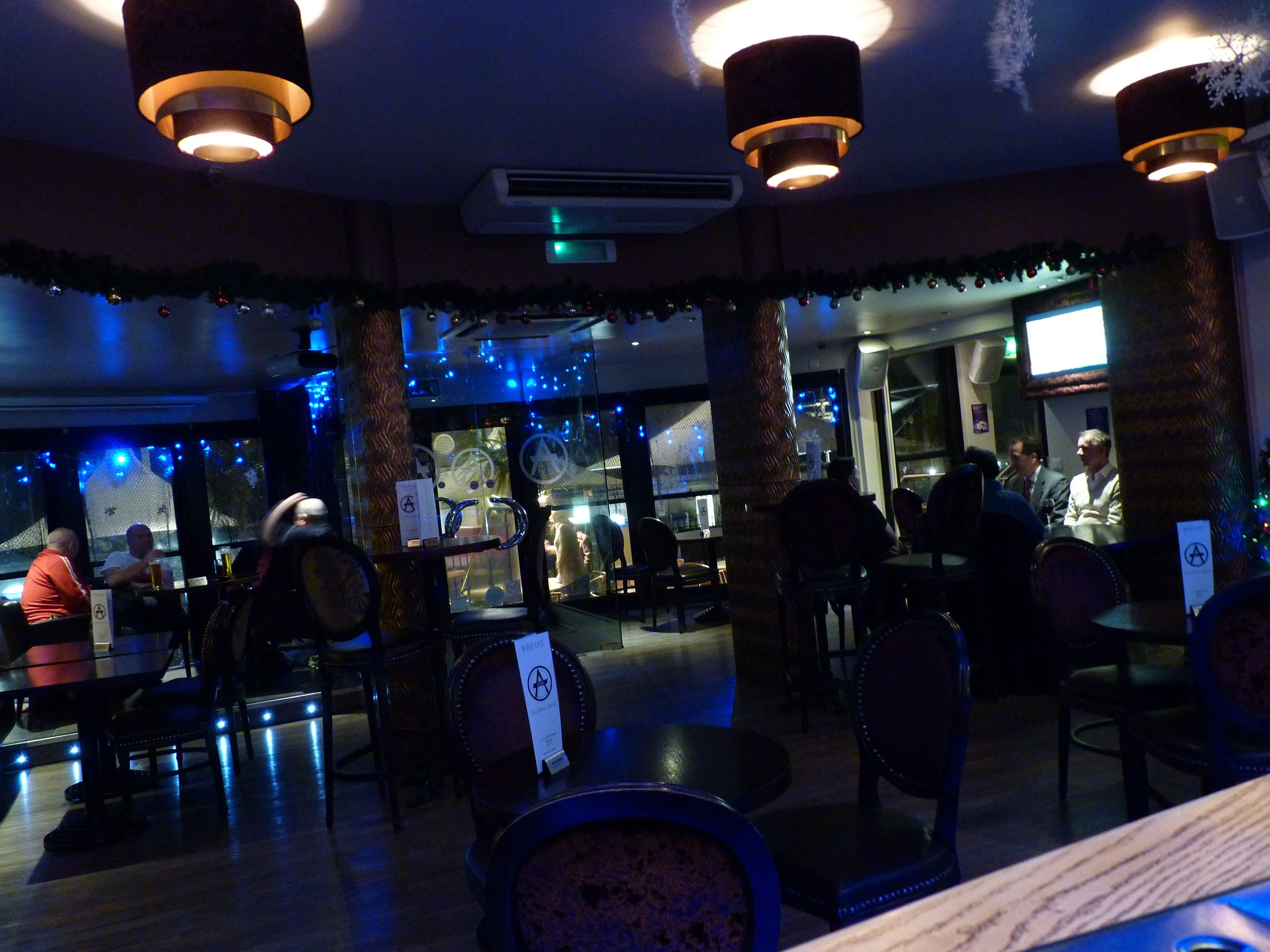 An indoor dining area with tables and chairs, a Christmas tree, and a large window.