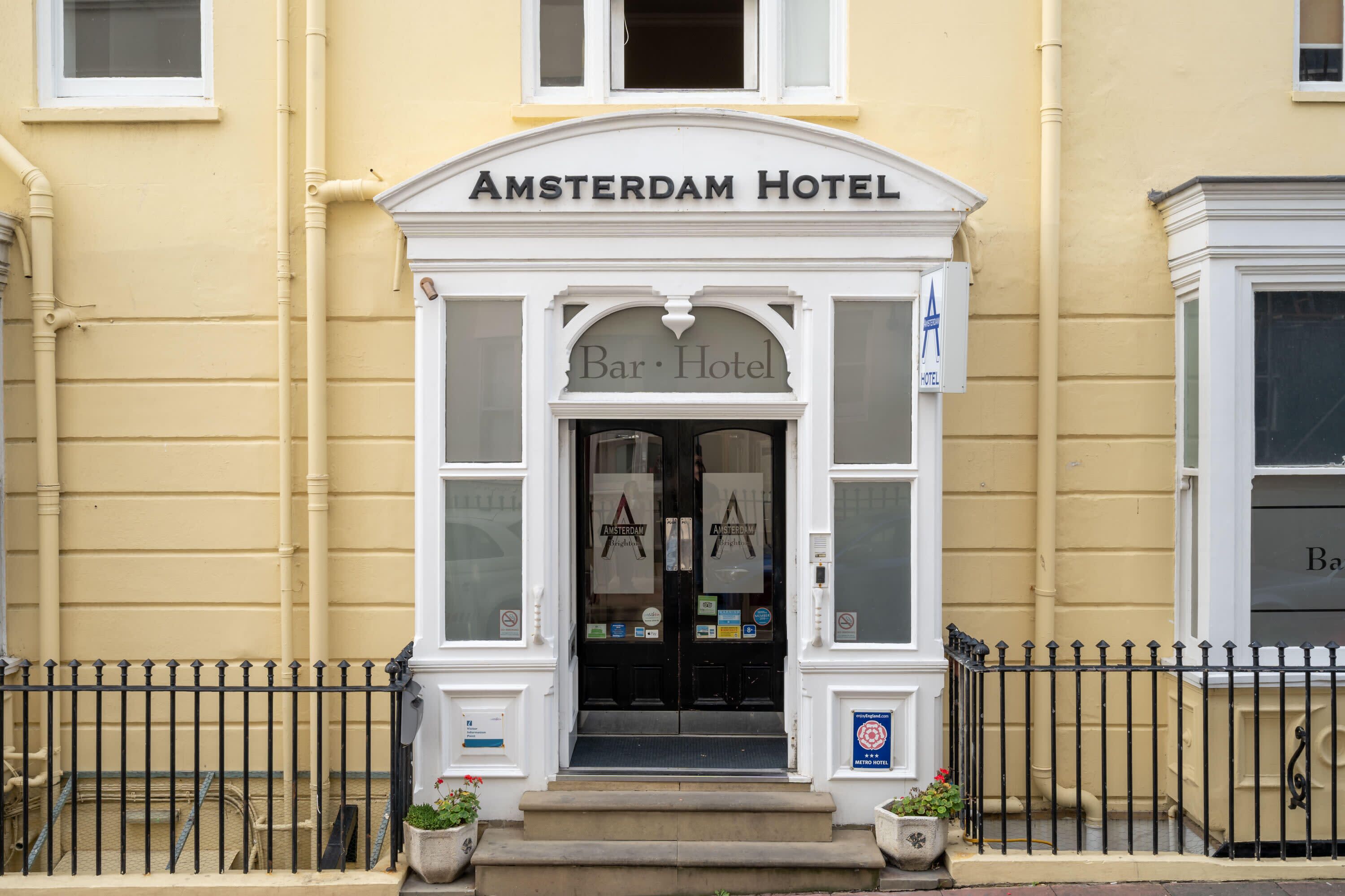 Entrada del Hotel Amsterdam con un letrero que dice Bar Hotel, una puerta negra y una fachada blanca.