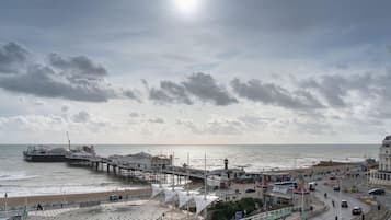 A pier extending into the sea with a walkway and a building with a clock tower.