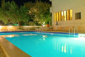A swimming pool with a blue interior, surrounded by lounge chairs and a tree. - Hotel Esperides (Ierapetra)