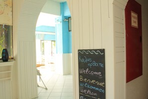 A hallway with a chalkboard sign reading "Welcome" in multiple languages. - Hotel Esperides (Ierapetra)