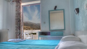 A bedroom with a bed, a desk, and a view of the outdoors.