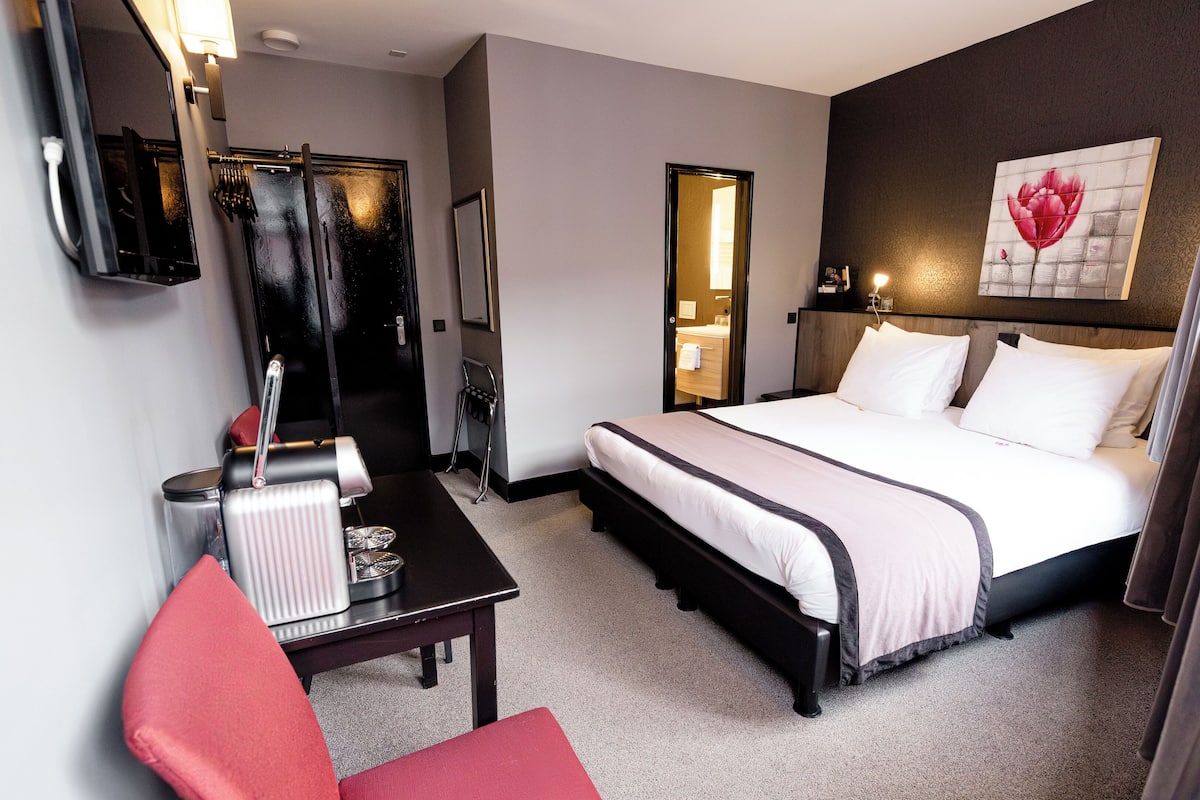Une chambre d’hôtel équipée d’un lit, d’un bureau, d’une chaise, d’un miroir et d’un espace douche.