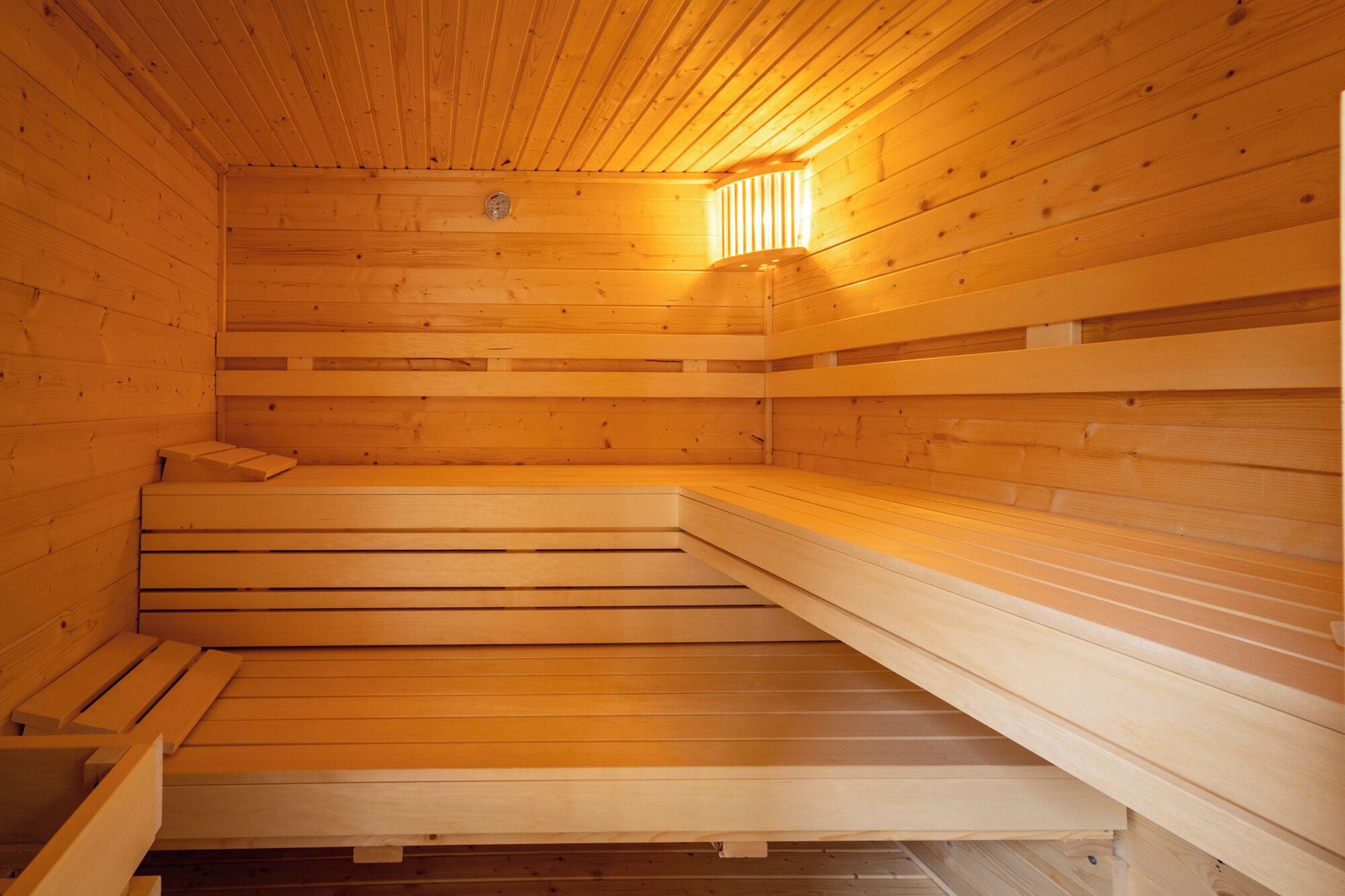 A sauna with wooden benches and a sloped floor.