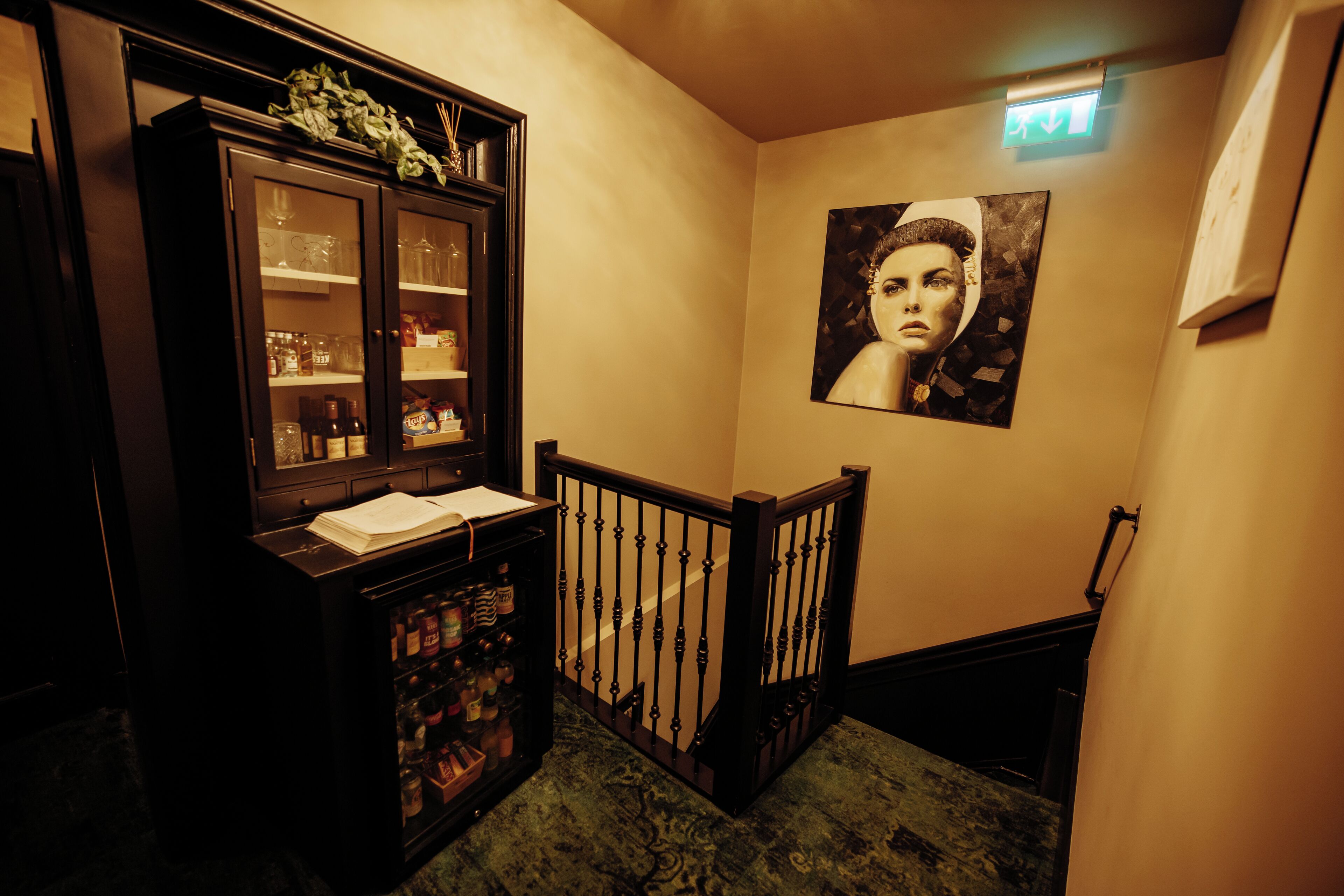 A staircase with a wooden railing, a cabinet with glass doors, and a framed picture on the wall.