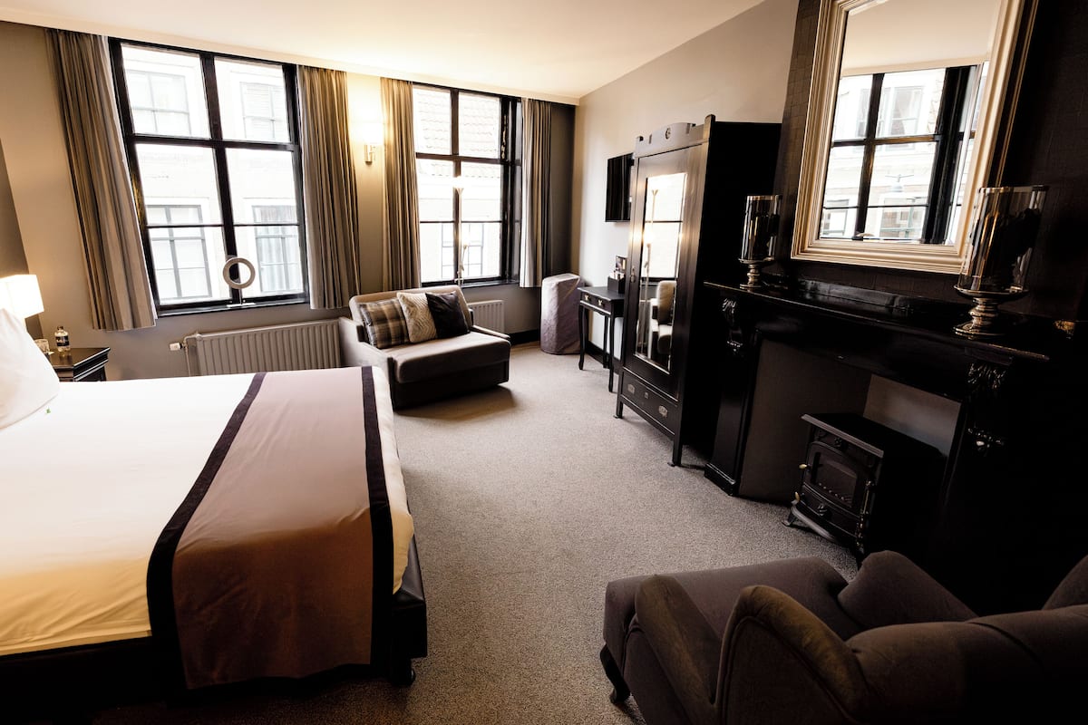 Une chambre d’hôtel avec un grand lit, un canapé, un bureau et une cheminée.