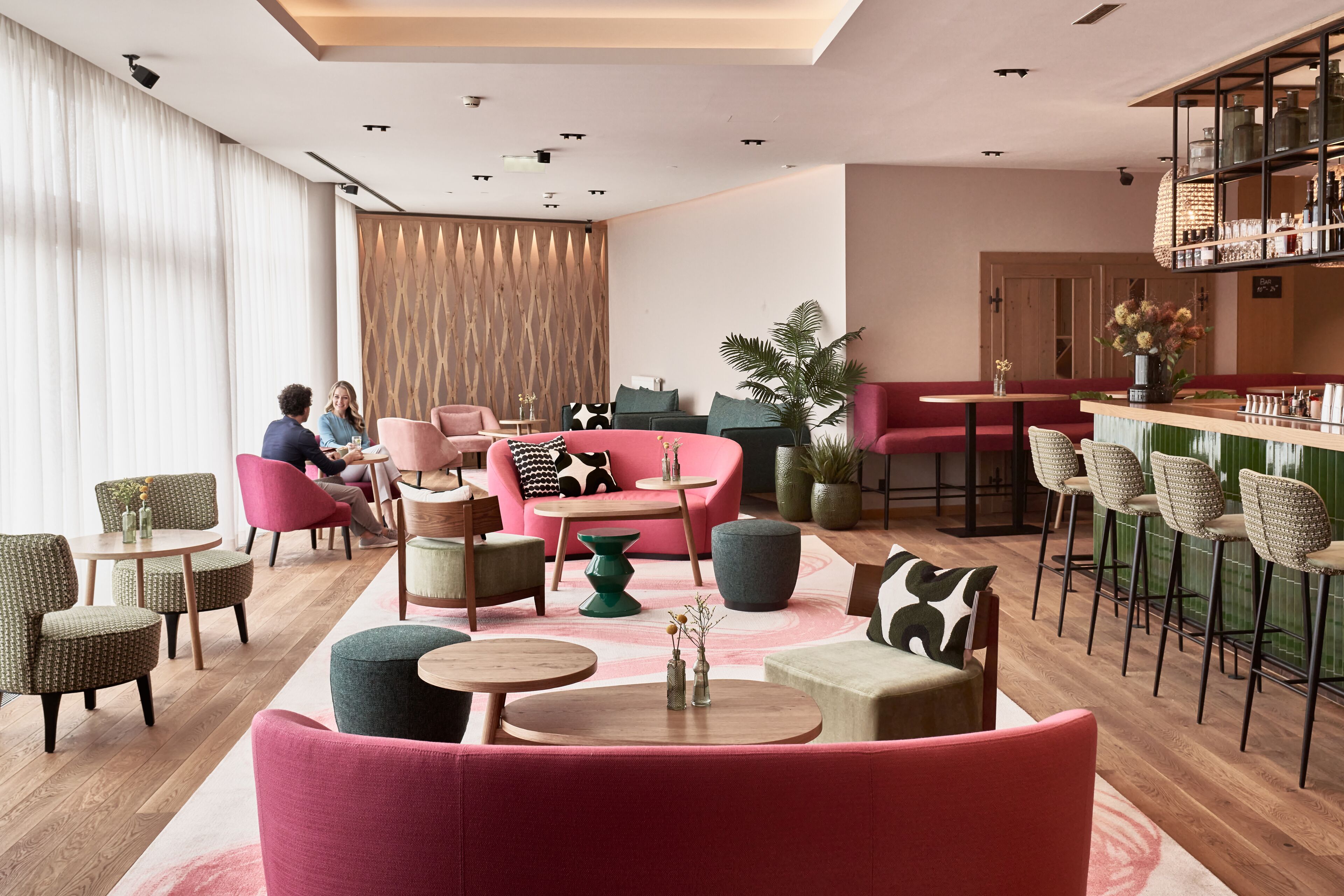 A modern lounge area with seating arrangements, a bar, and a kitchen area.