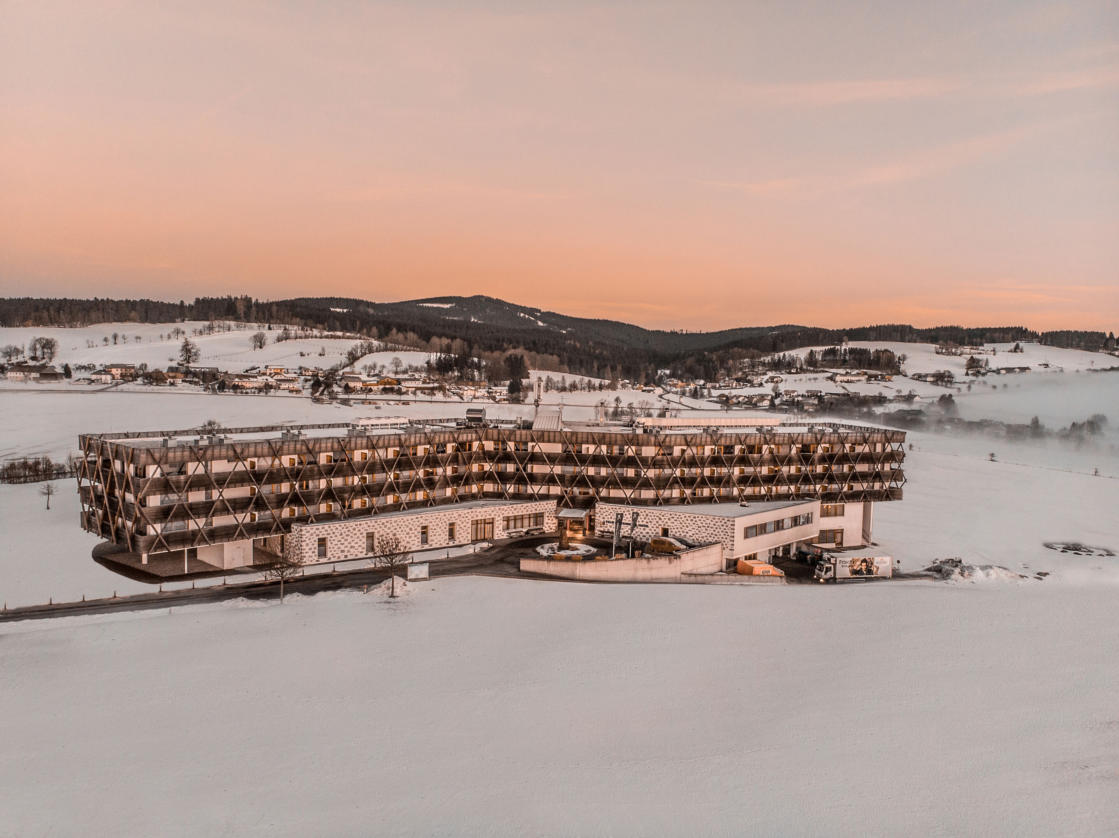 Un hotel de varios pisos con un diseño arquitectónico único, rodeado de un paisaje nevado.