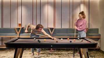 A pool table in a room with a sofa and a small table with a lamp.
