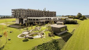 A modern building with a unique geometric facade, surrounded by a well-maintained lawn and a small pond.