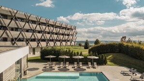 A modern hotel with a pool area, outdoor seating, and a view of the countryside.