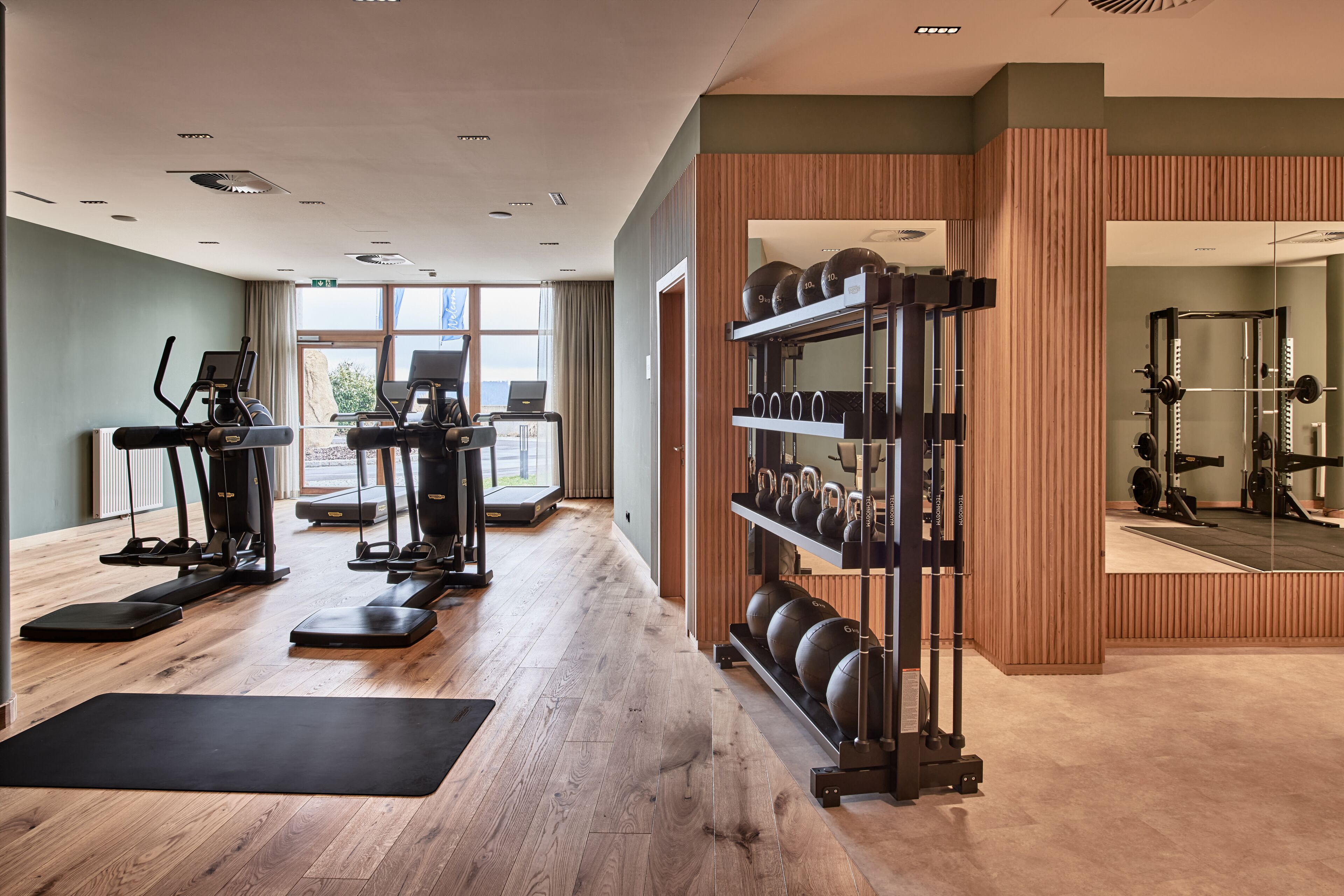A gym with treadmills, elliptical machines, and a weight rack.