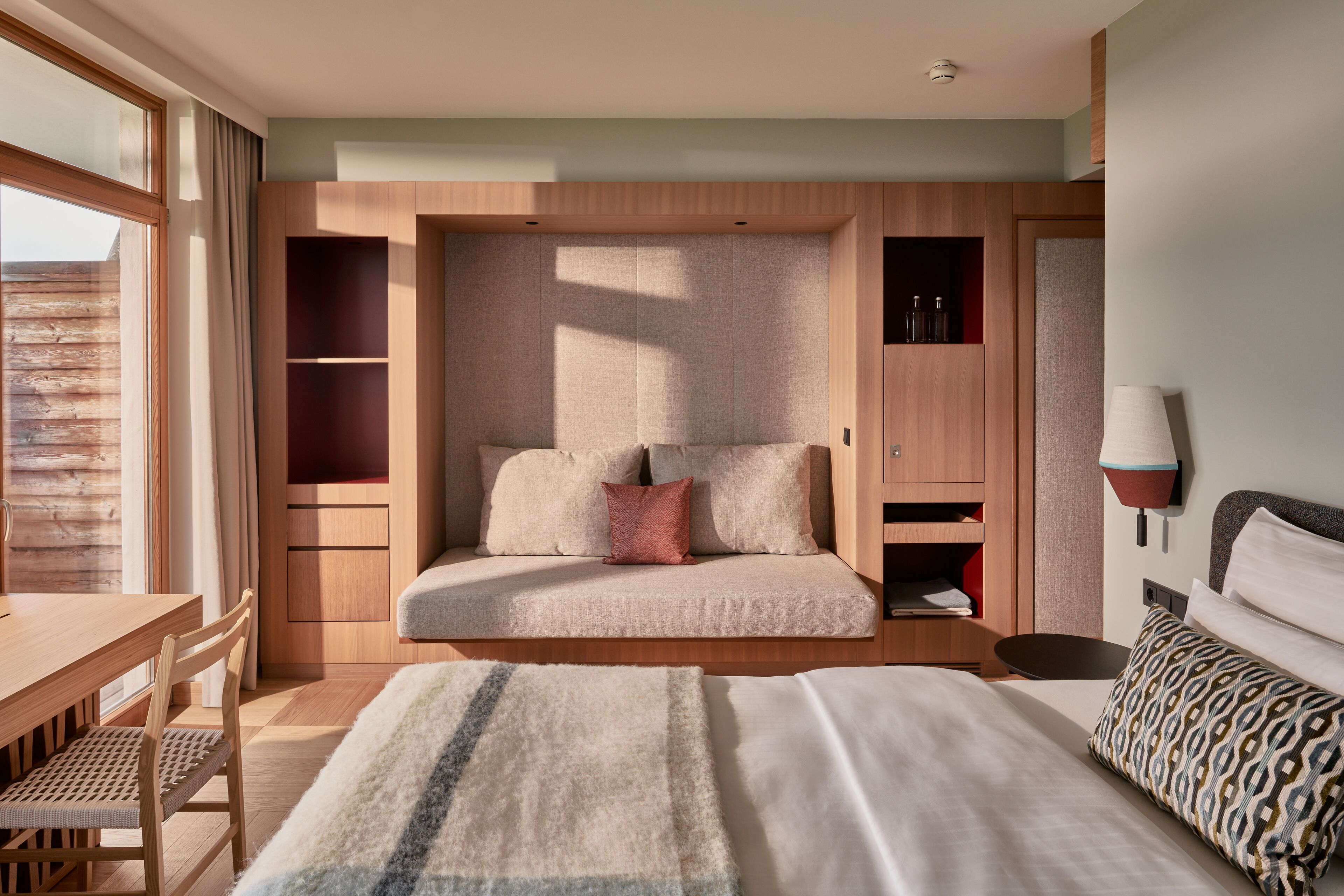 Ein modernes Hotelzimmer mit einem großen Bett, einer Schlafcouch, einem Holztisch und einem Essbereich.