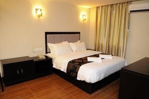 A hotel room with a bed, nightstand, and a wardrobe.