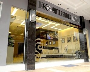 The exterior of the Waterfront Hotel with a modern glass facade and a prominent logo. - KK Waterfront Hotel (Kota Kinabalu)
