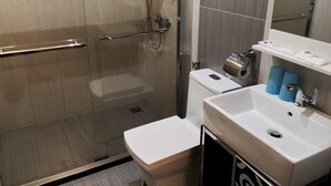 Une salle de bain moderne avec une douche à parois de verre, un lavabo blanc et des toilettes.