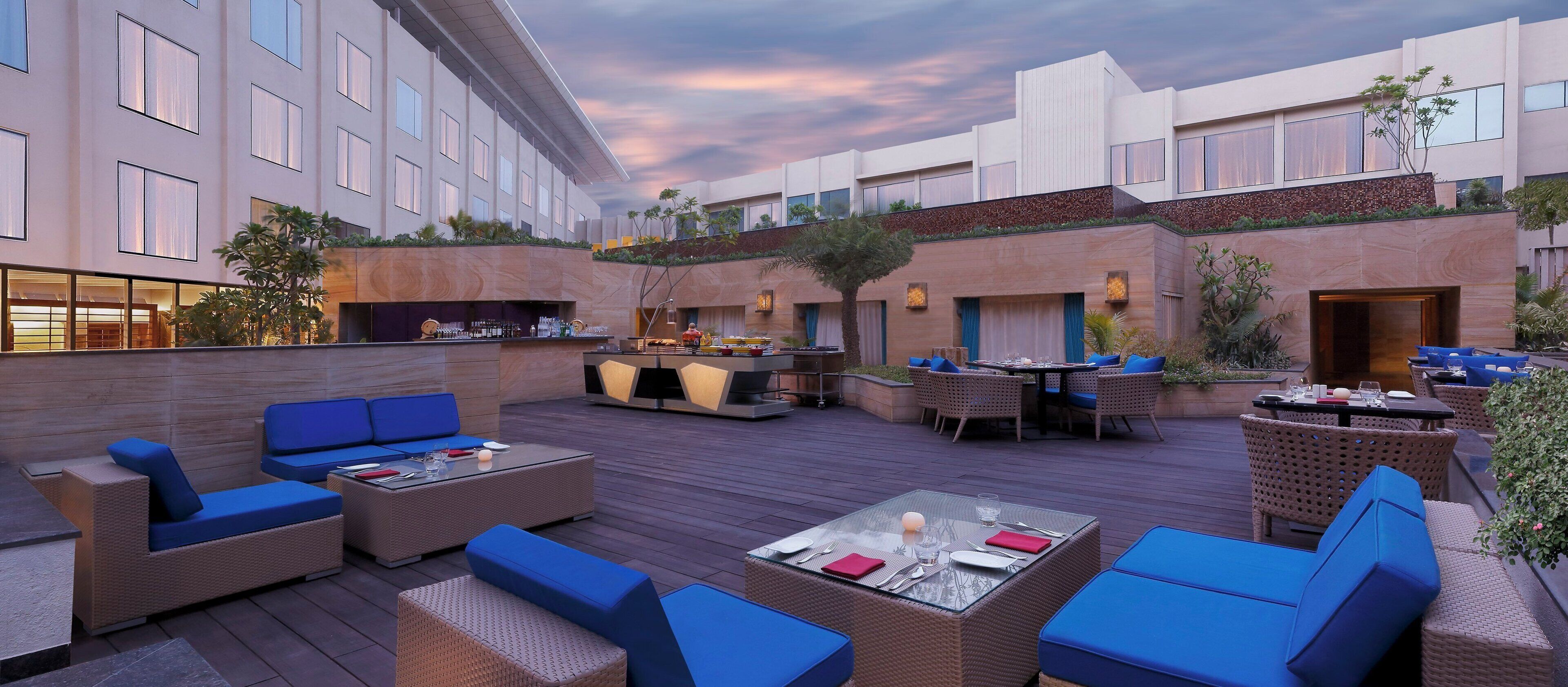 Un patio al aire libre con mesas y sillas, un bar y vistas del exterior del edificio.