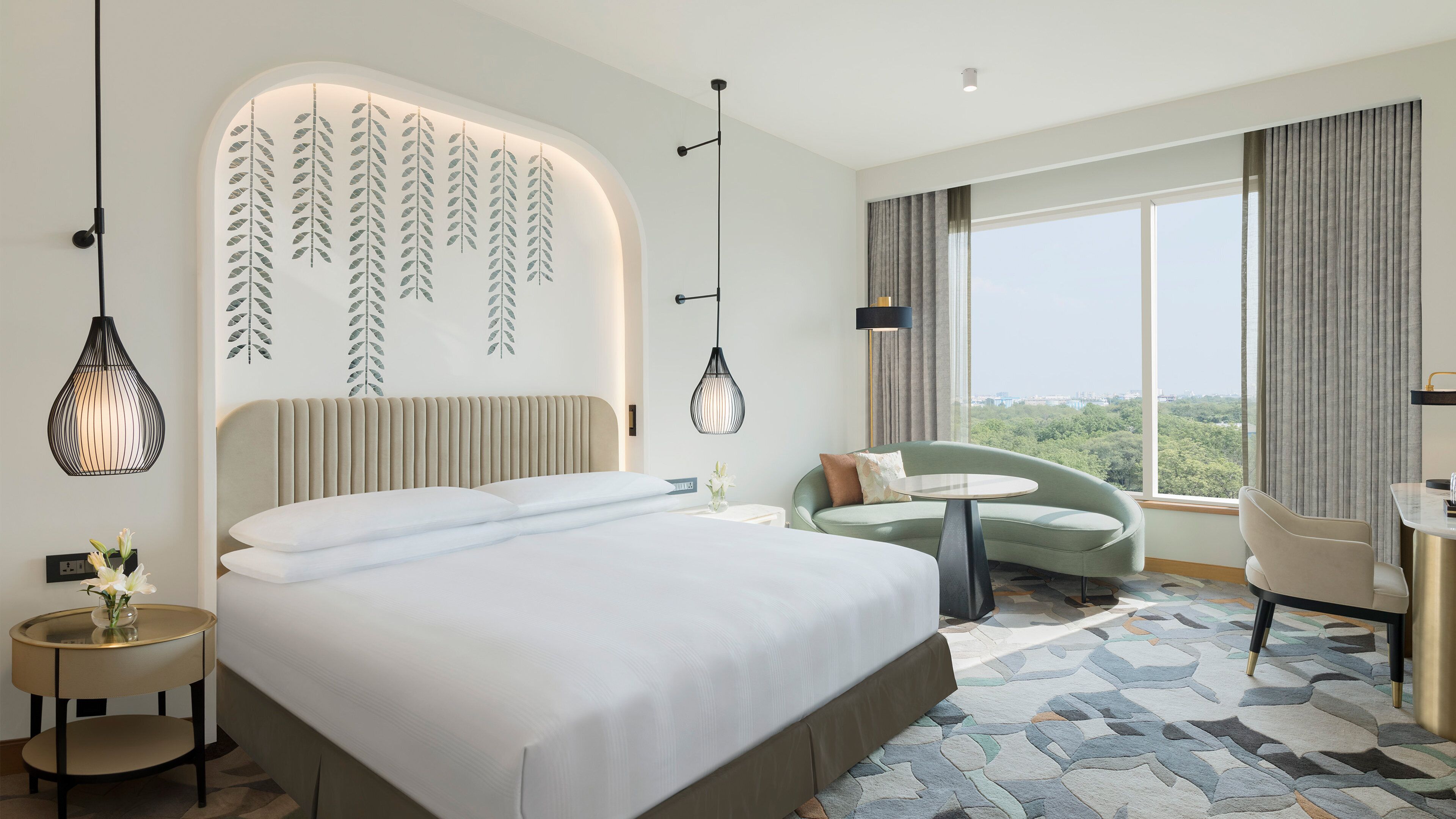A hotel room with a large bed, a seating area with a view, and a desk.