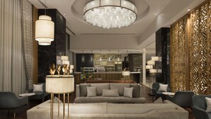 Eine moderne Hotellobby mit einer zentralen Sitzecke, einer Bar und einer dekorativen Wand.