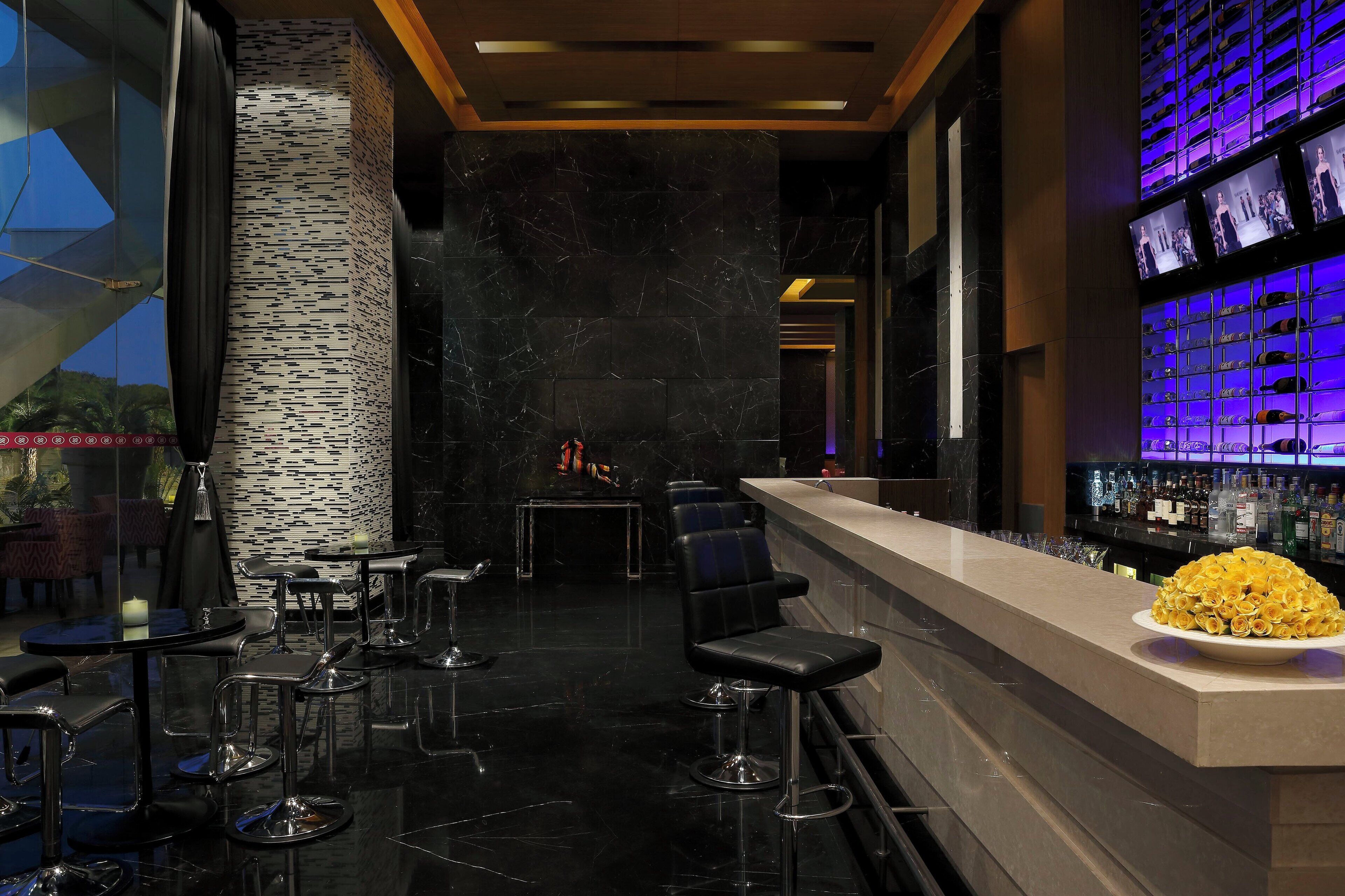 Eine moderne Bar mit hohen Hockern, einer Theke und einer Flaschendisposition.