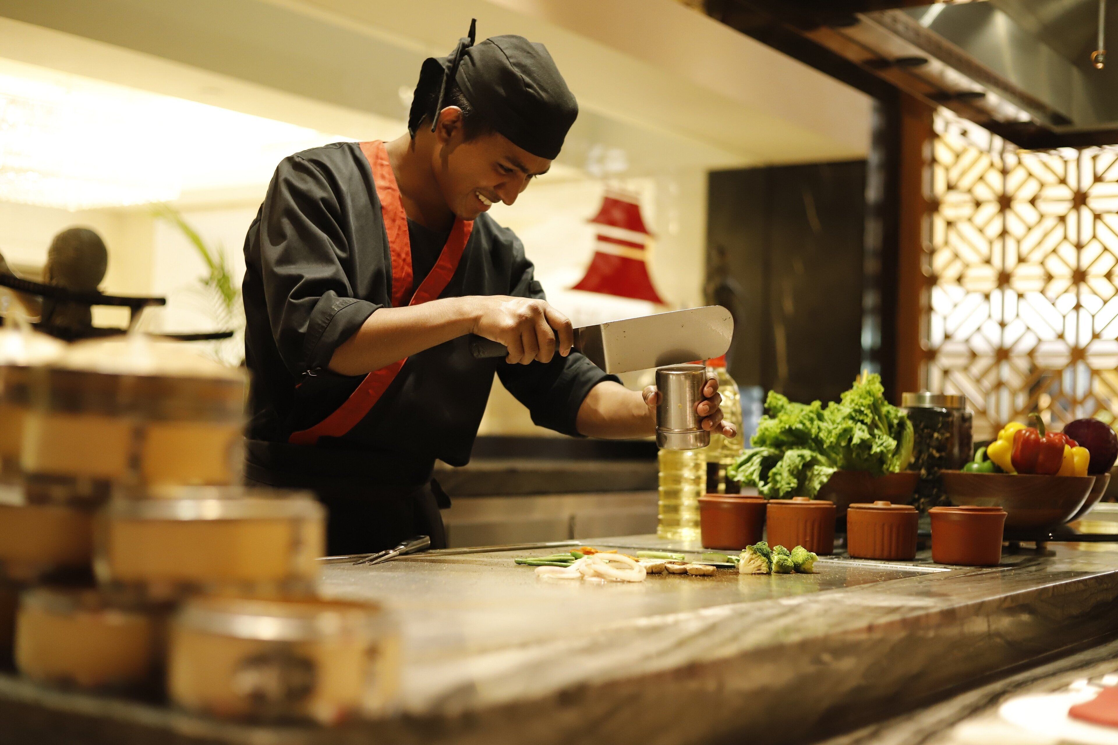 A chef preparing food in a kitchen with a wooden countertop, a cutting board, and various ingredients.