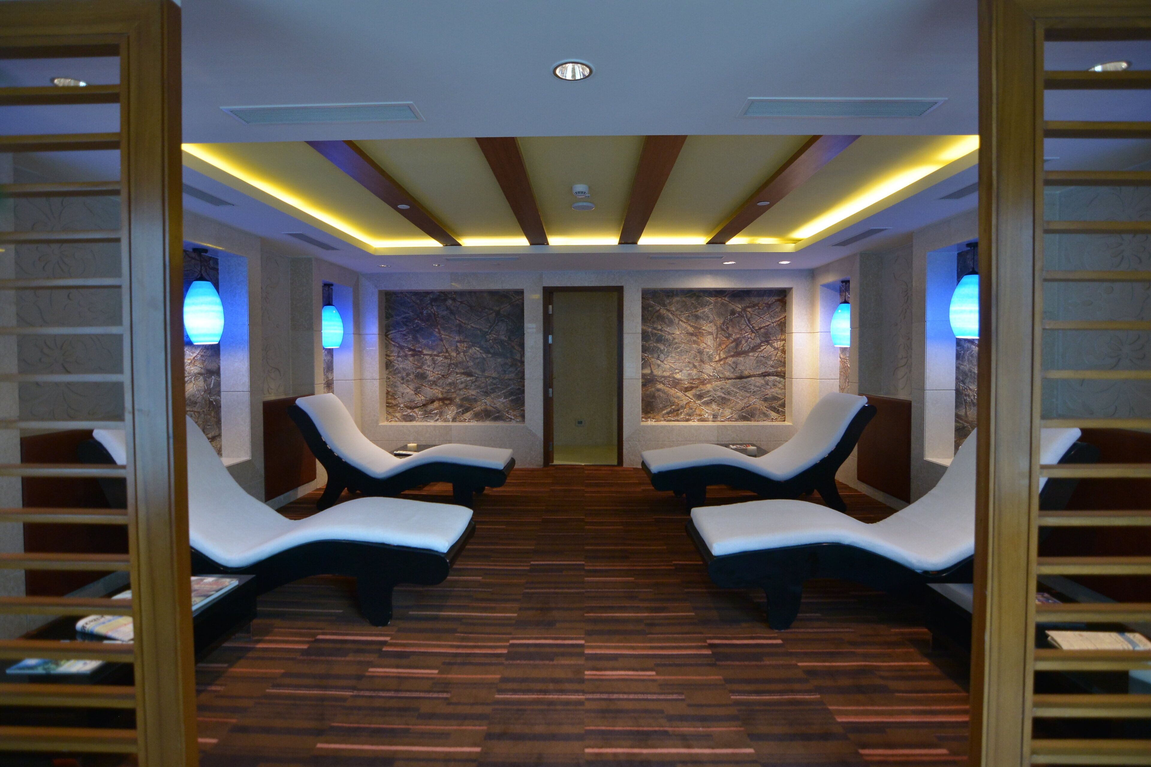 A spa room with four reclining chairs, wooden flooring, and wall-mounted massage tables.