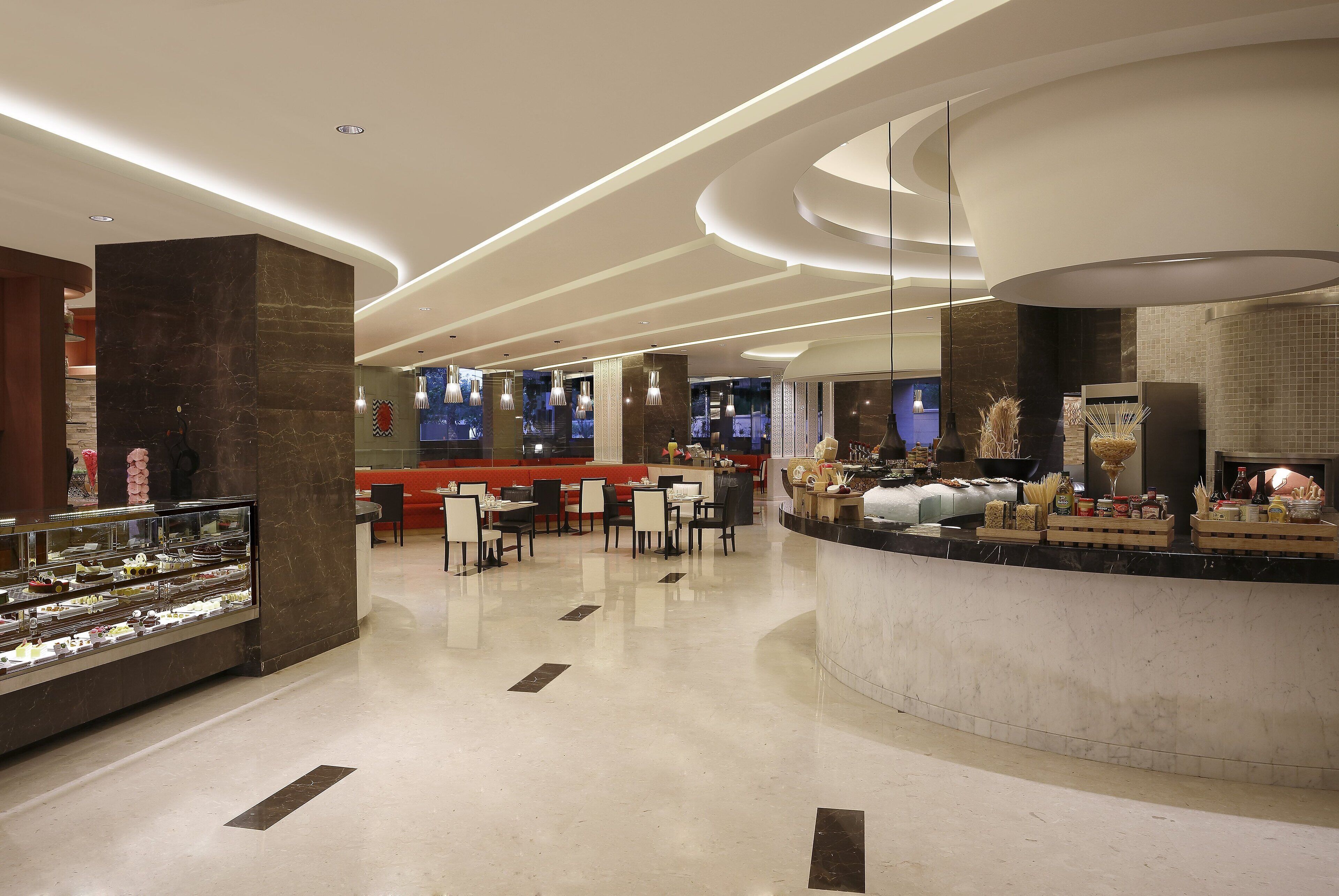 A modern hotel lobby with a central bar area, seating arrangements, and a display case with items.
