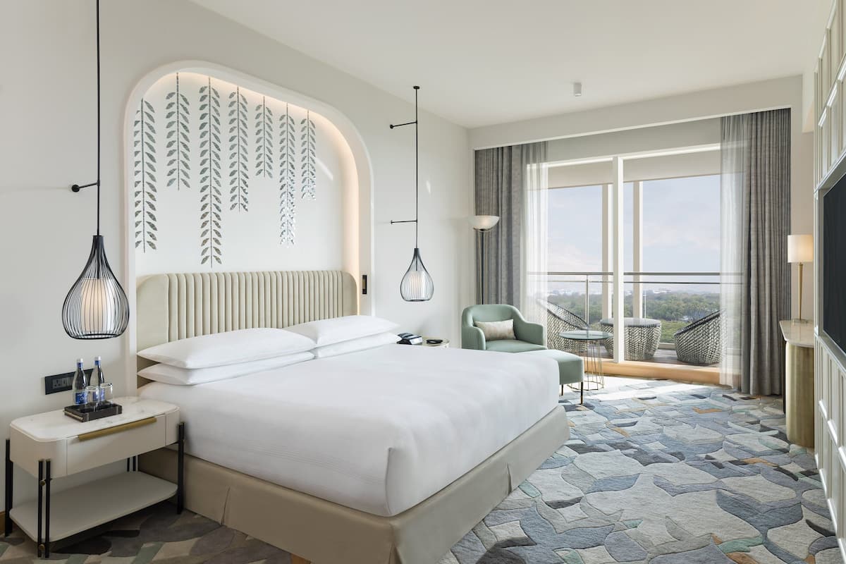Een moderne hotelkamer met een groot bed, een bureau, een stoel en een balkon met uitzicht.