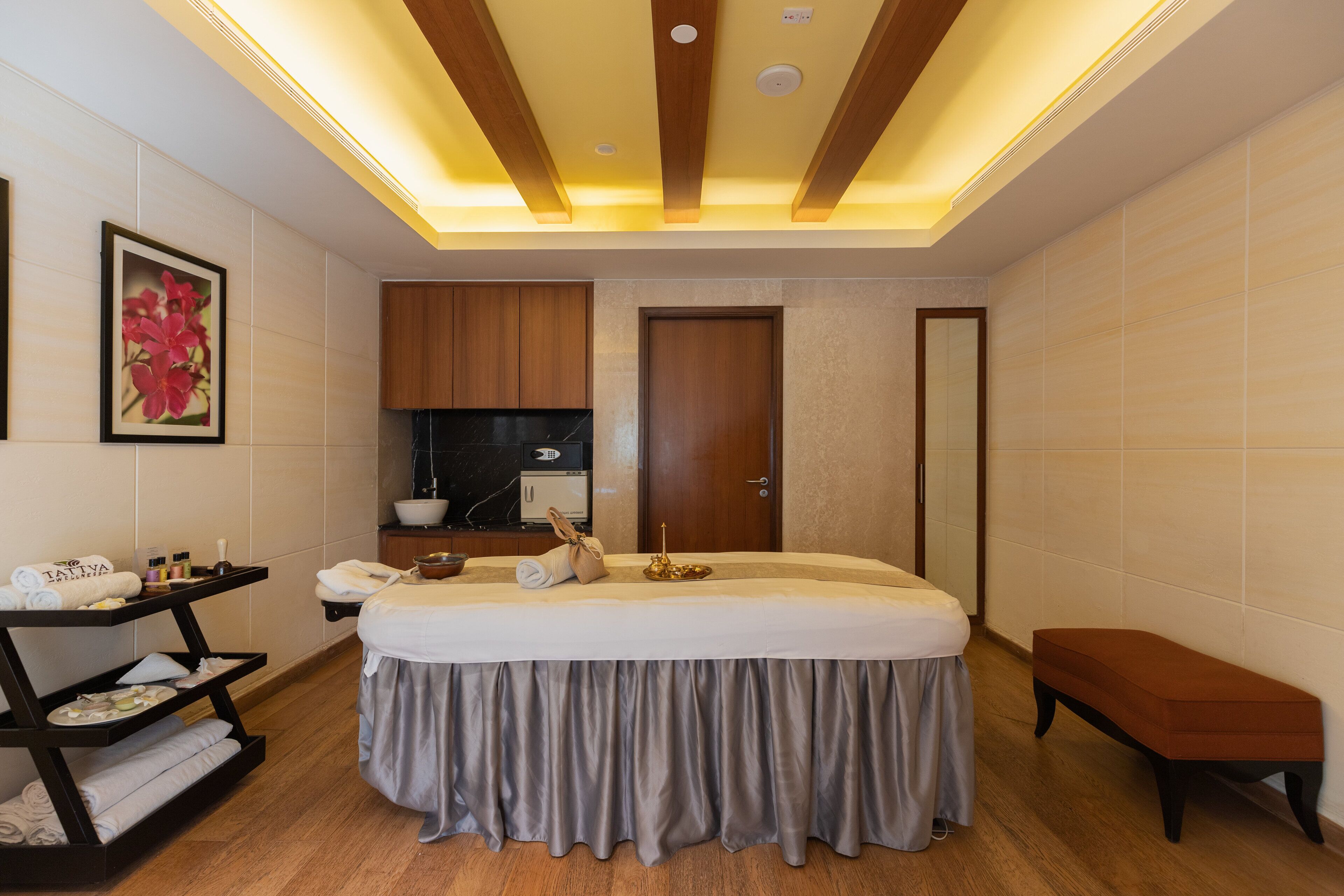 Quarto moderno com cama, mesa de cabeceira e um banquinho.