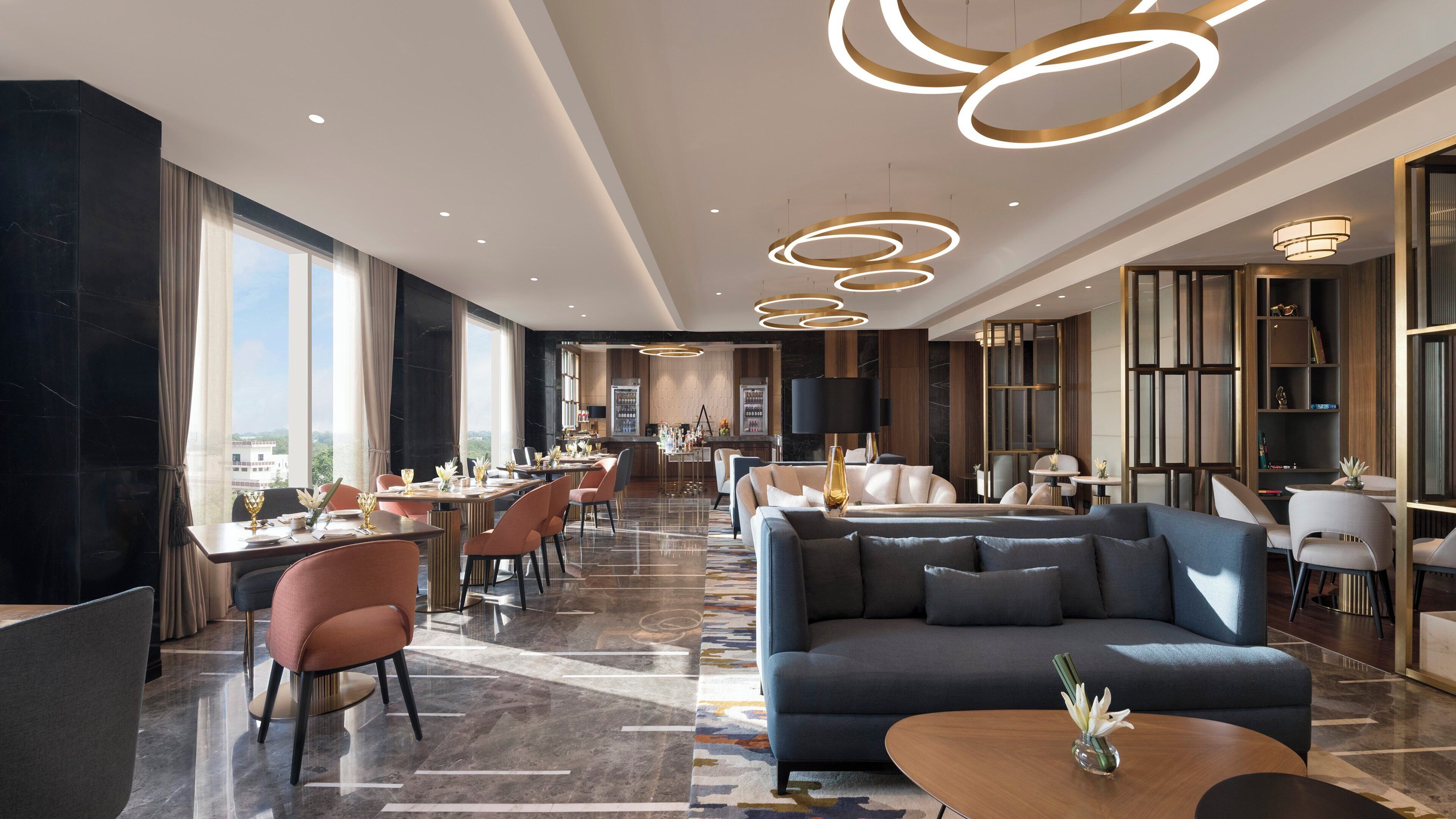Um hall de hotel moderno com área de refeições, assentos e vista para a cidade.