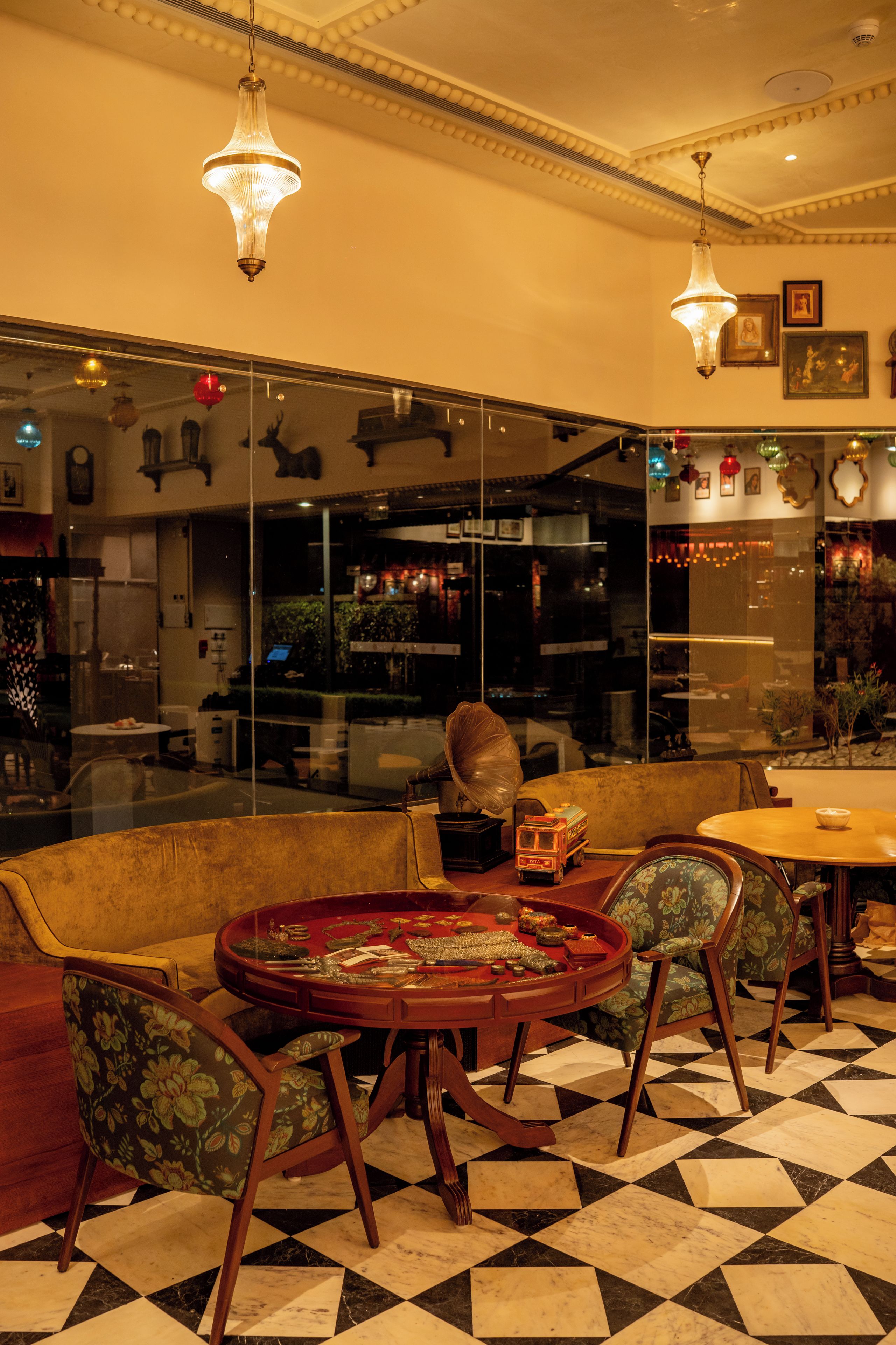 A room with a checkered floor, a round table with chairs, a sofa, and a decorative table with various items.