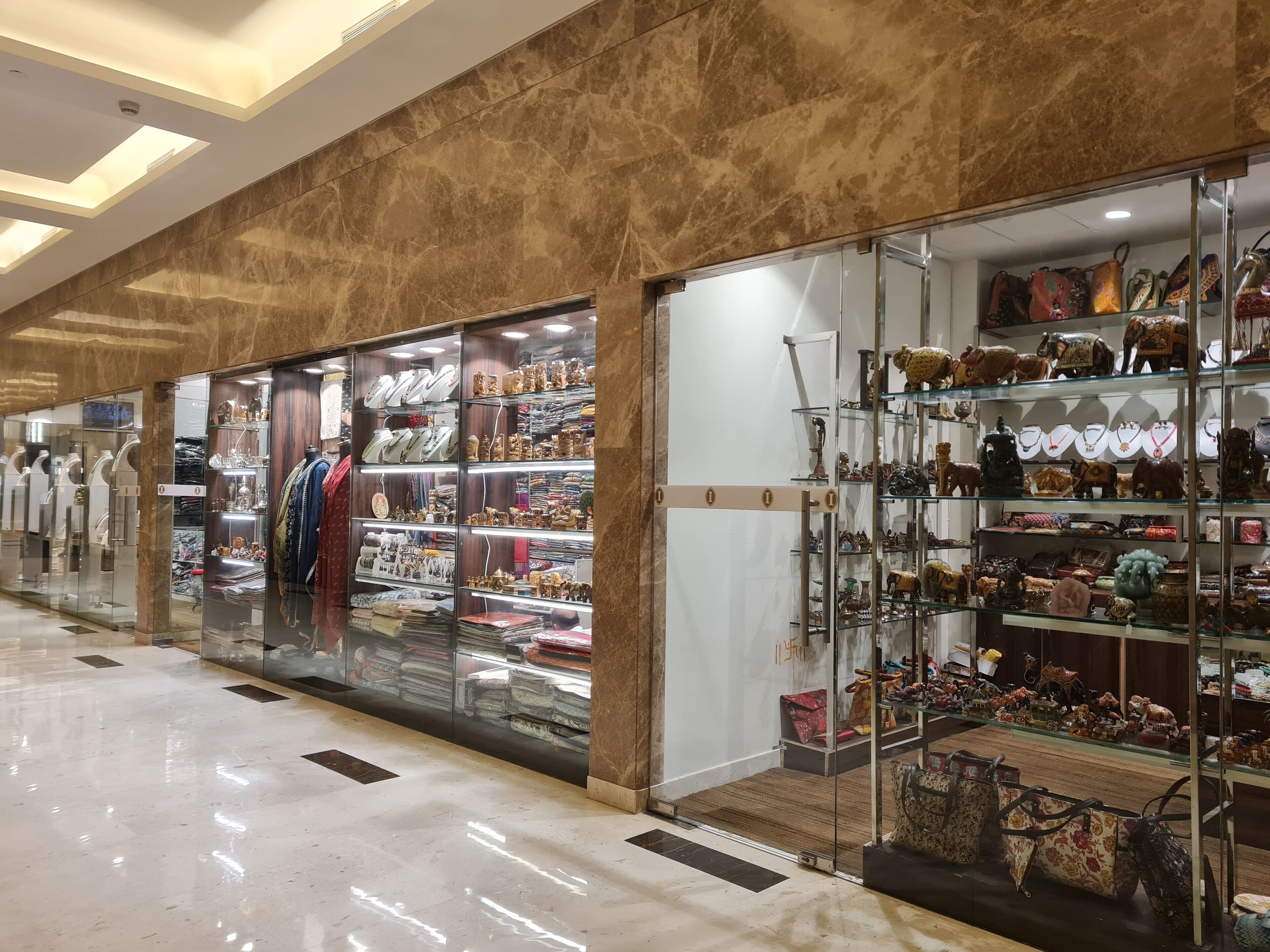 A shopping mall corridor with stores displaying jewelry and bags.