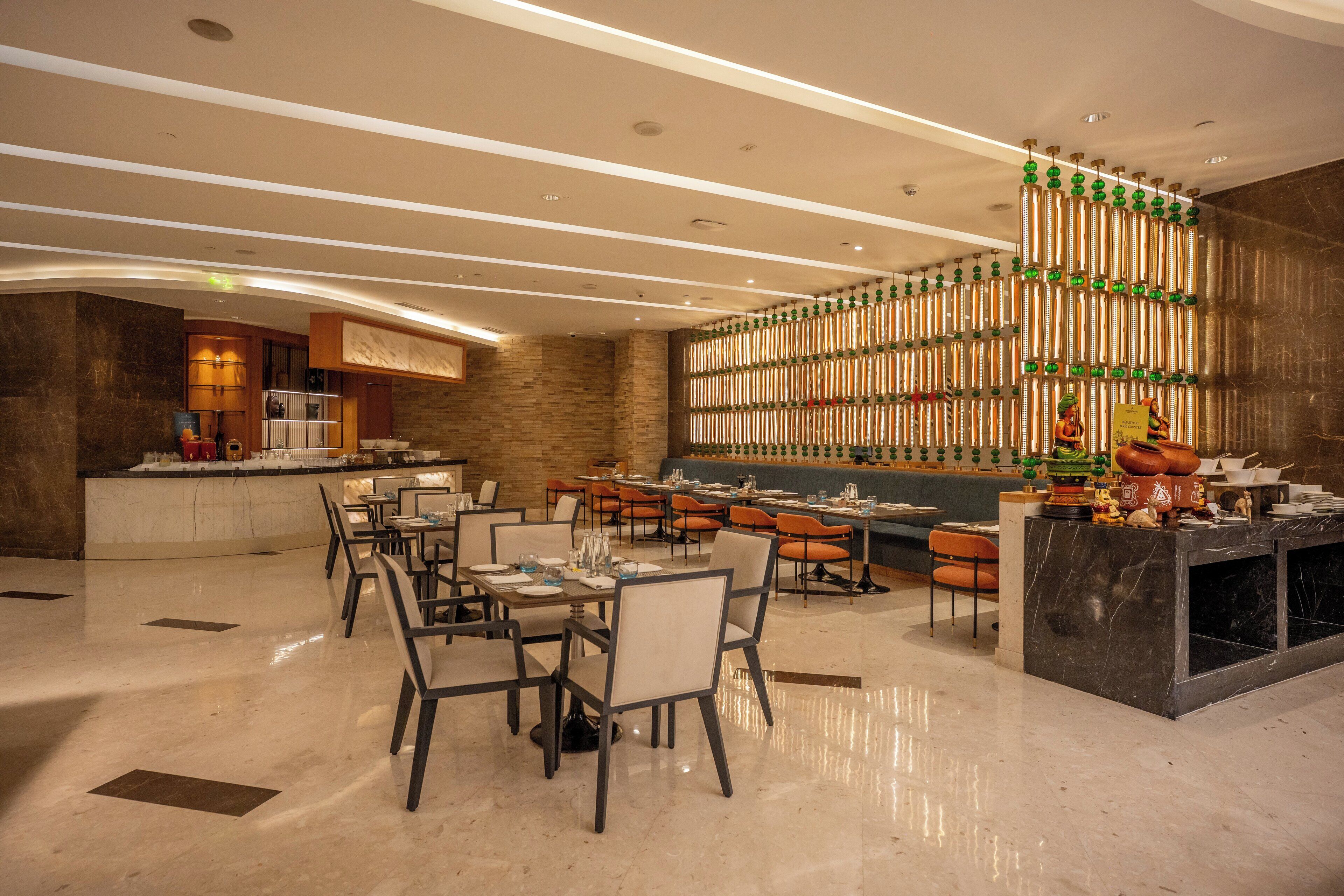 A modern restaurant with a bar area, marble flooring, and a stone accent wall.