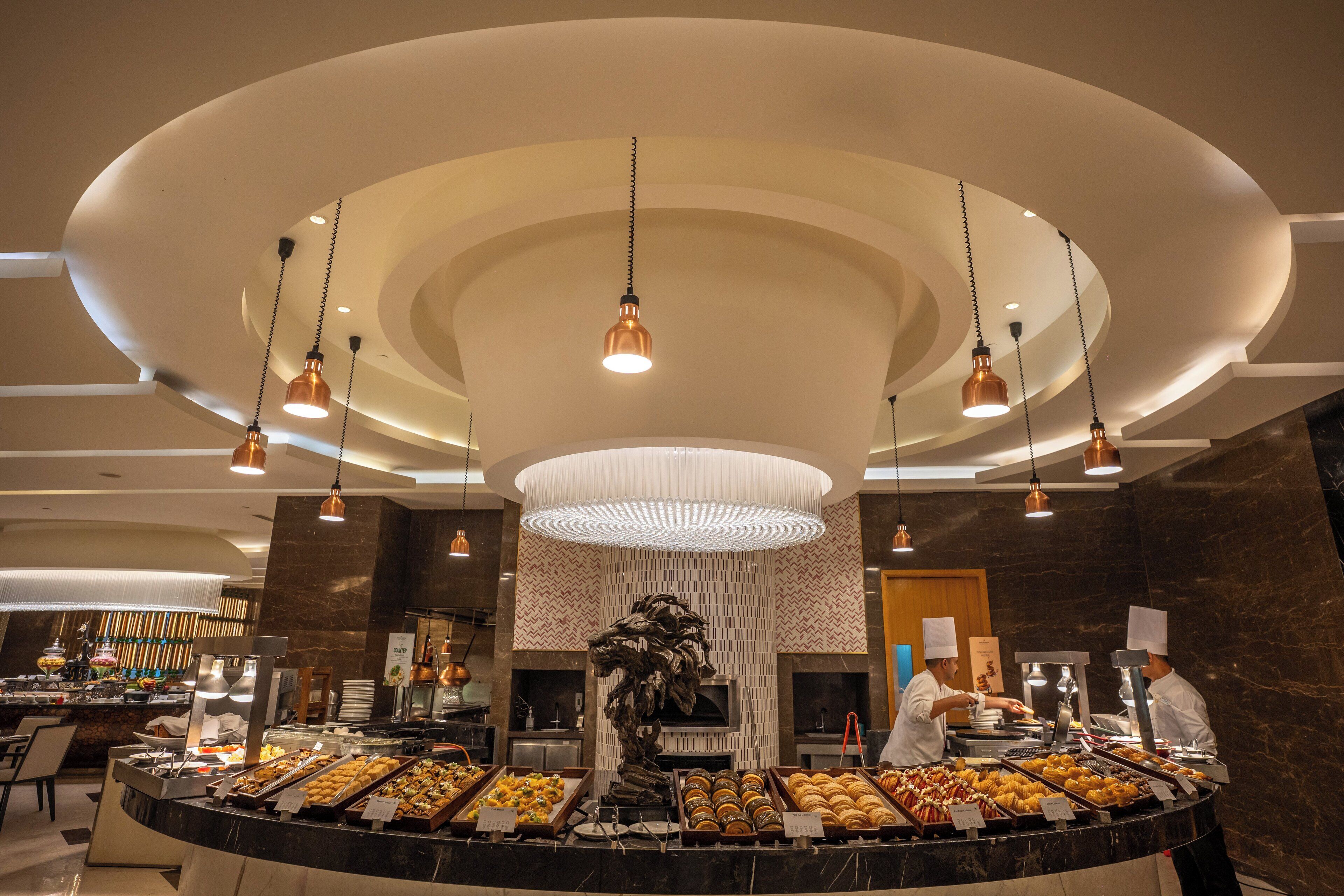 A buffet area with a central island, overhead lighting, and a marble wall.