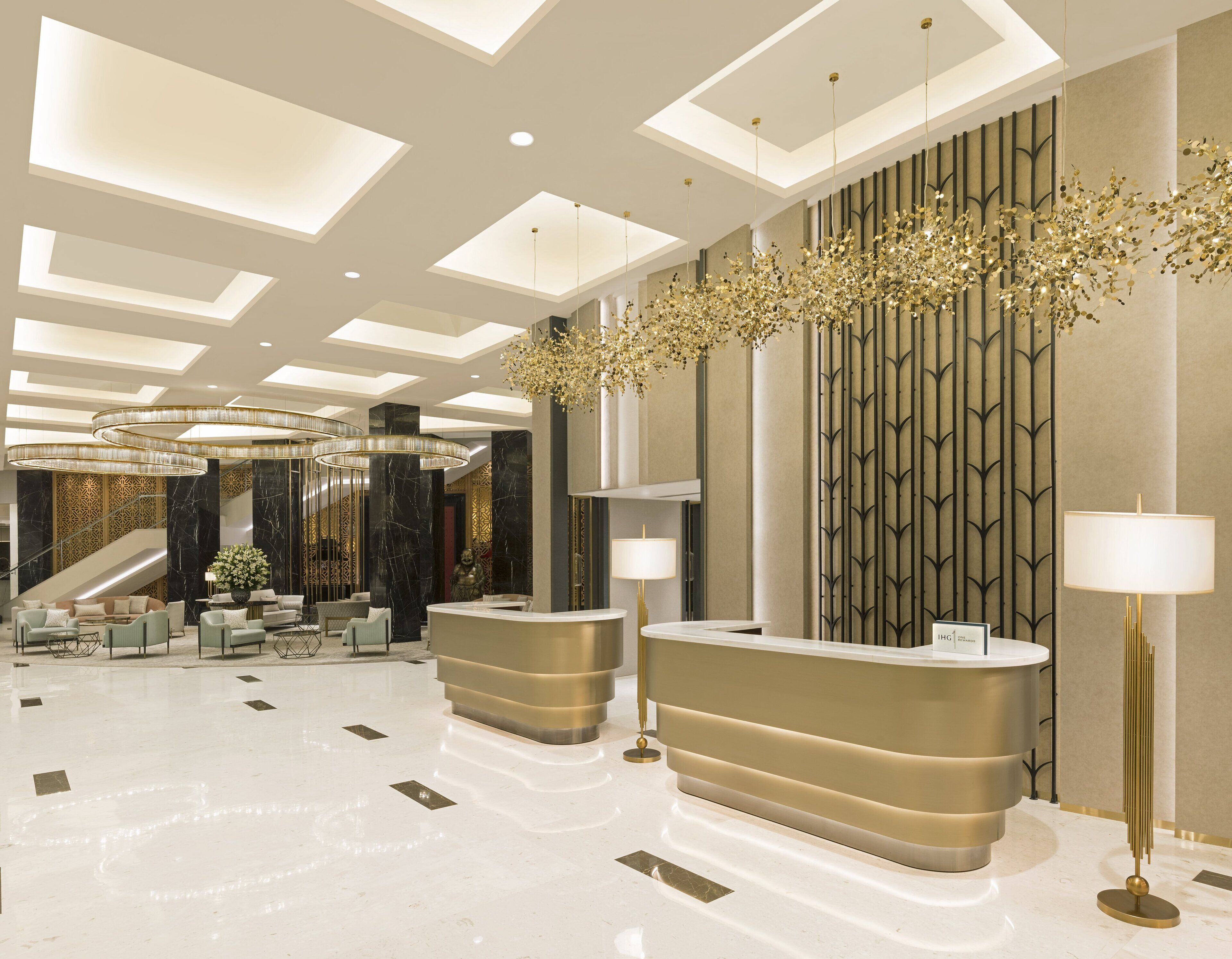 Un moderno vestíbulo de hotel con mostrador de recepción, zona de estar y una escalera.
