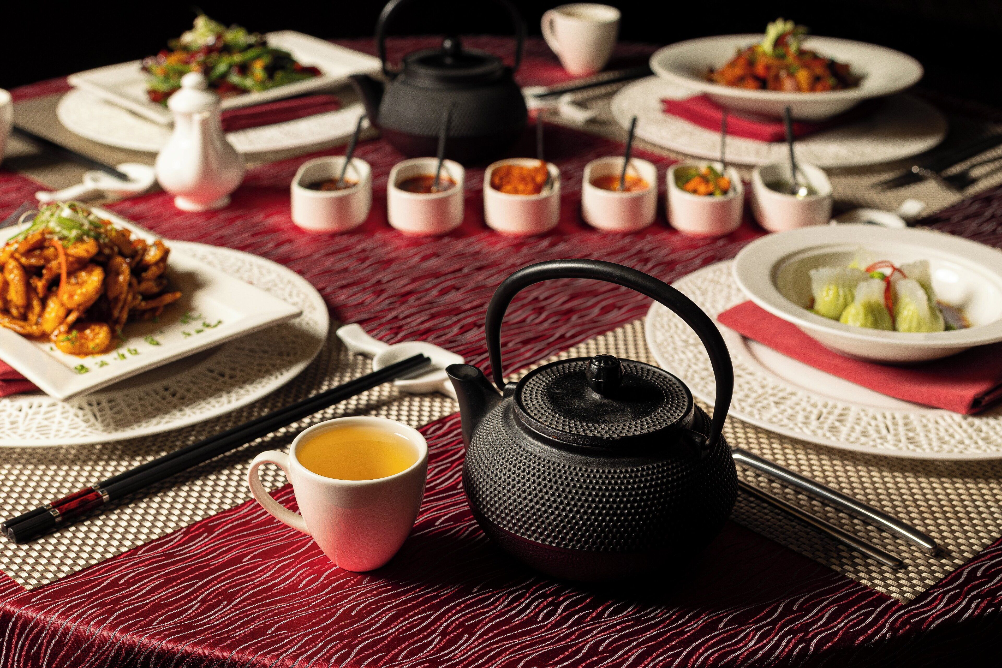A table set with a teapot, cups, chopsticks, and various dishes, suggesting a dining setup.