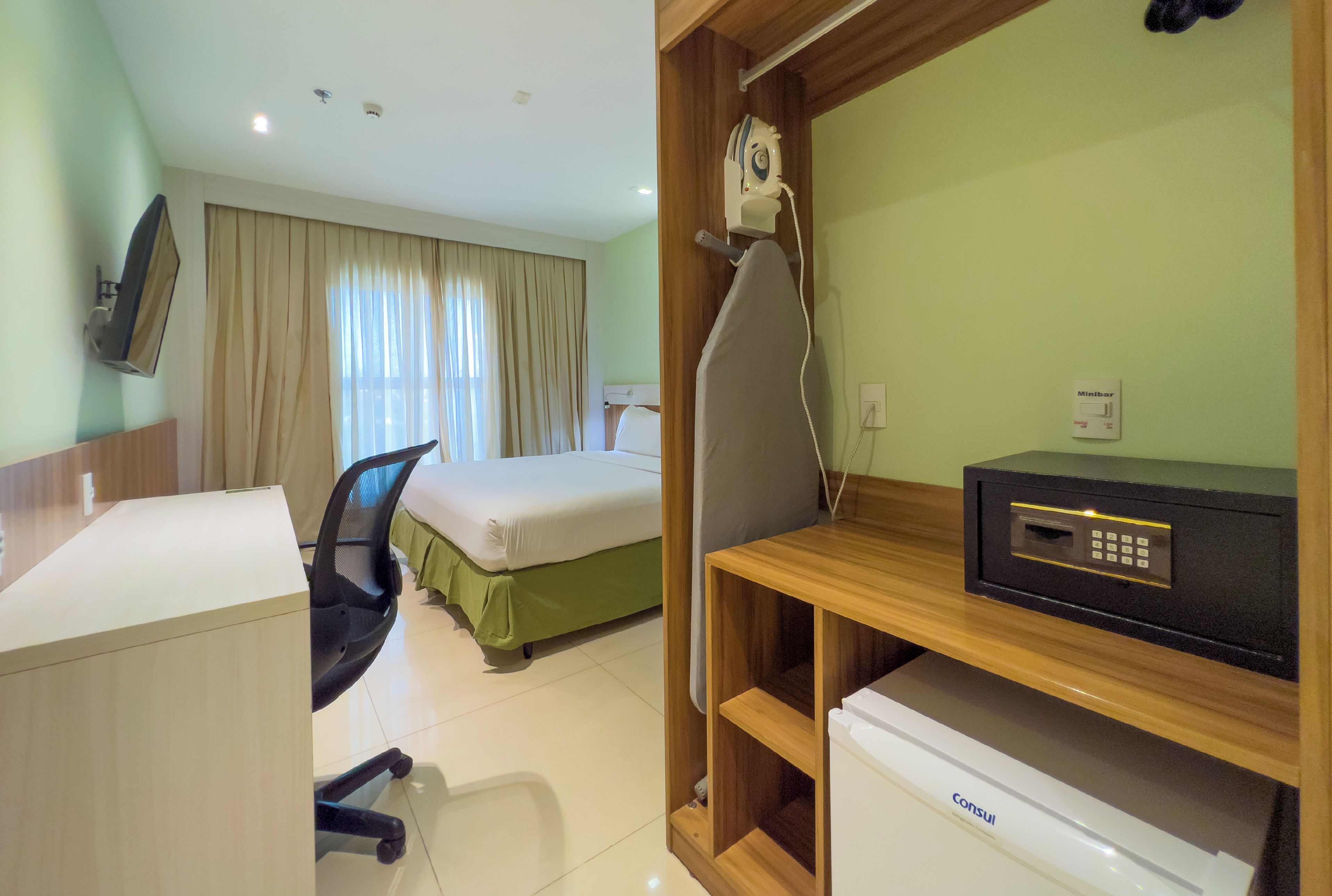 Habitación de hotel con escritorio, silla, cama y minibar.